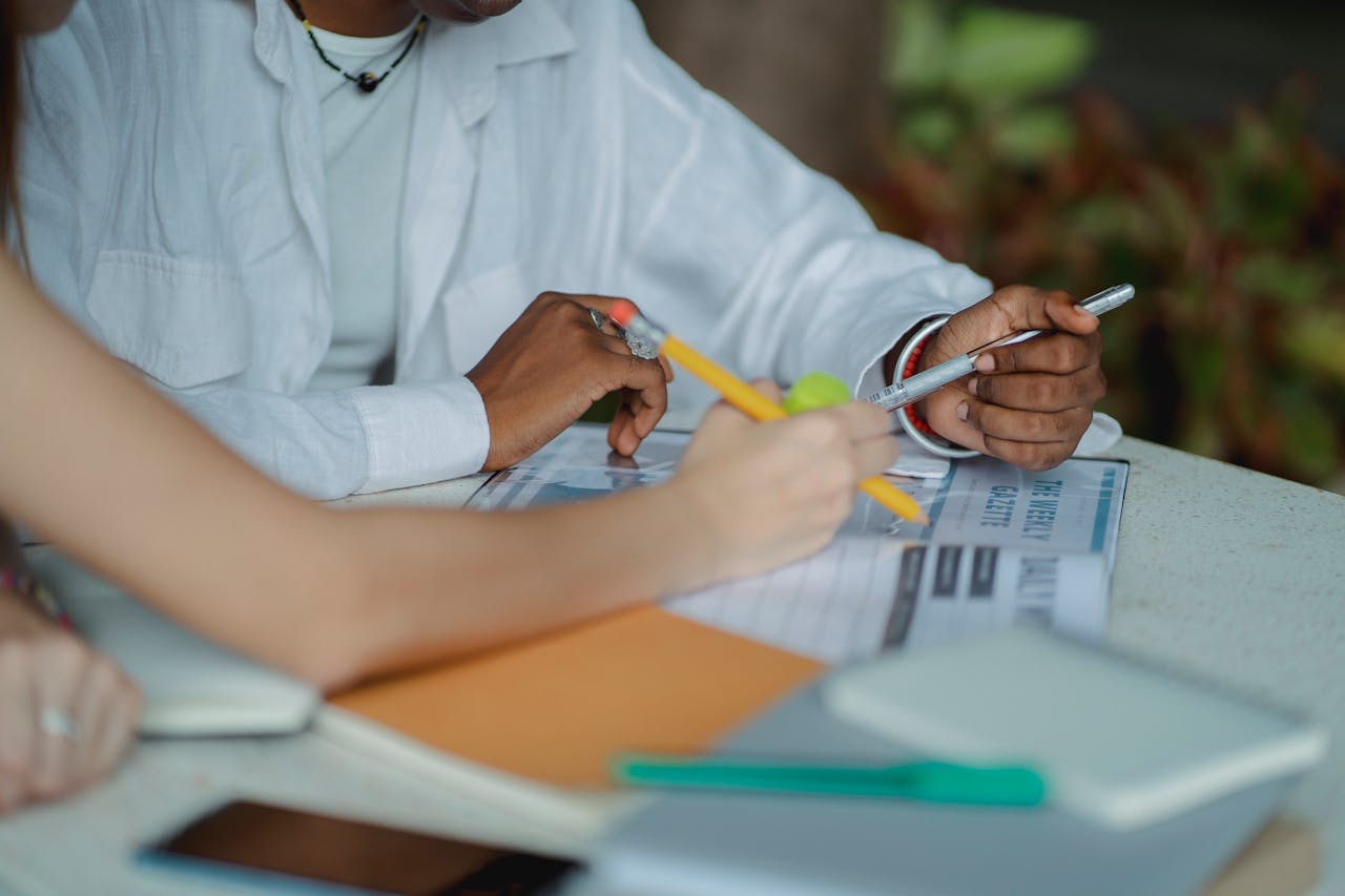 Crop anonymous multiracial female students sitting at table and doing academic project together